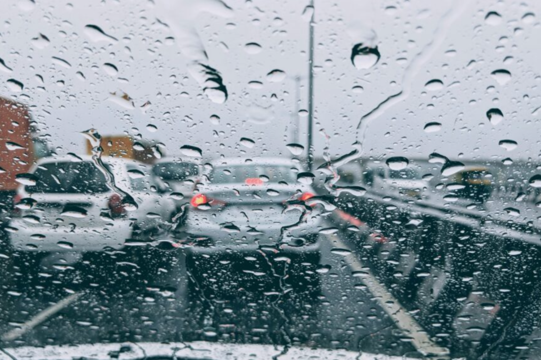 Vehicles driving on a rainy highway, including cars and trucks.