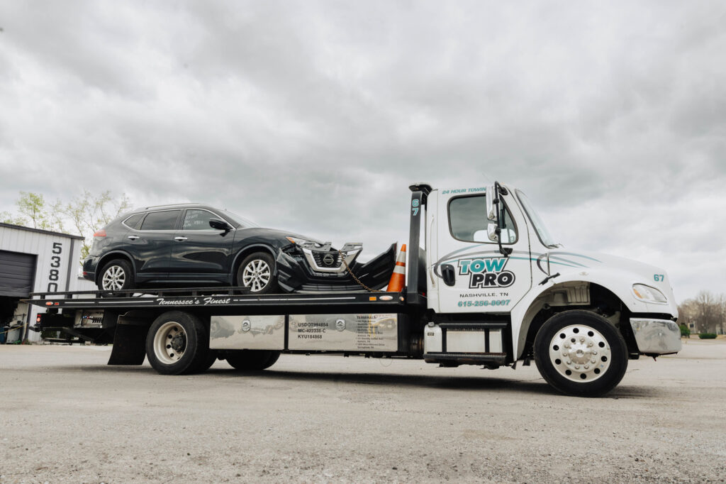 Tow Pro tow truck carrying a damaged SUV on a road in Nashville, TN.