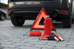 Roadside emergency kit with a reflective triangle, jumper cables, and flashlight.