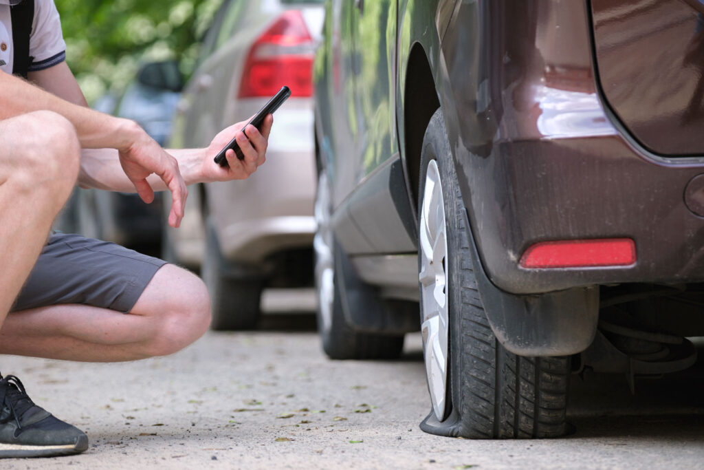 A vehicle with a flat tire safely parked on the roadside, waiting for assistance.