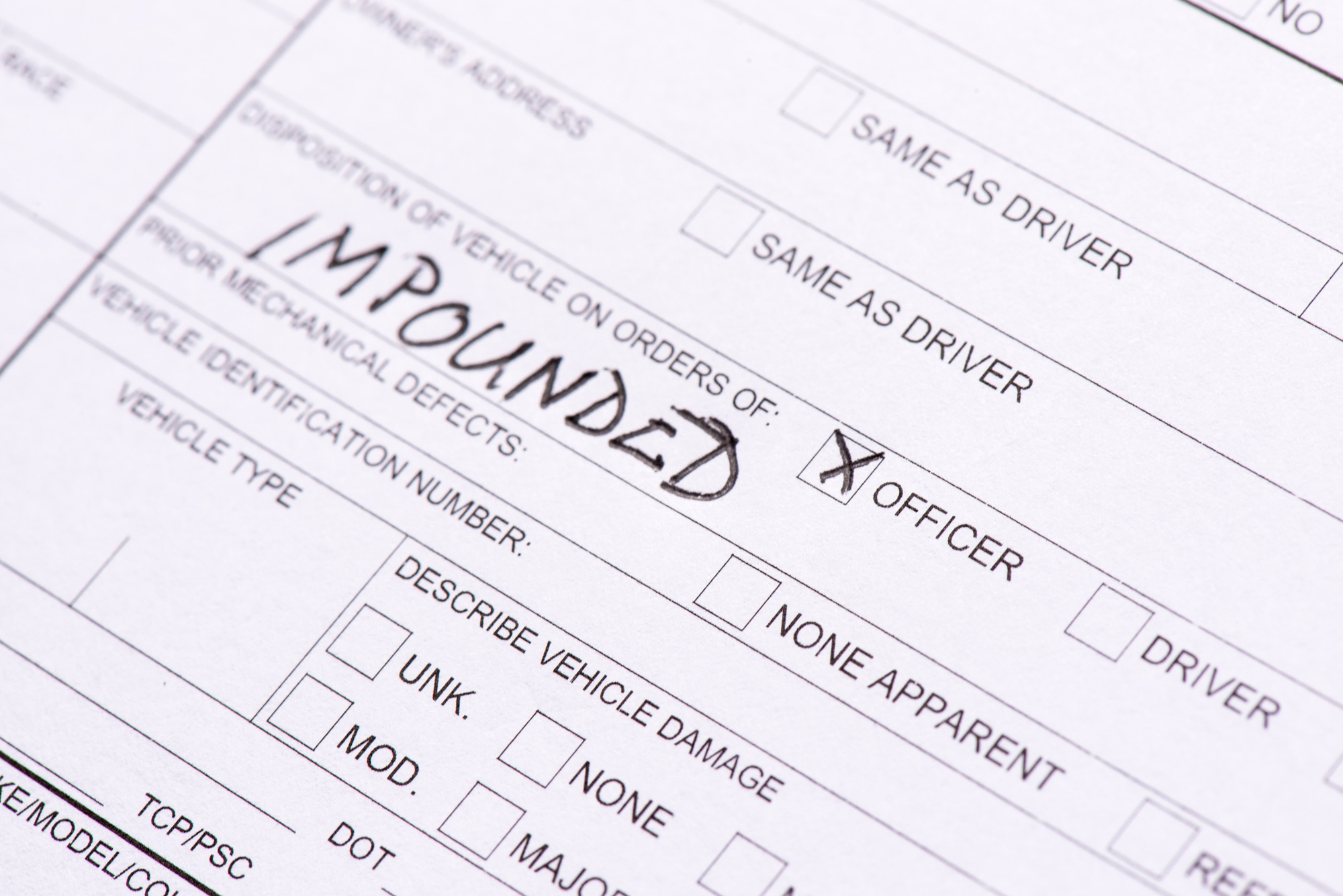 Close-up of a traffic collision report form showing a vehicle marked for impound by an officer as a result of an accident or traffic violation.