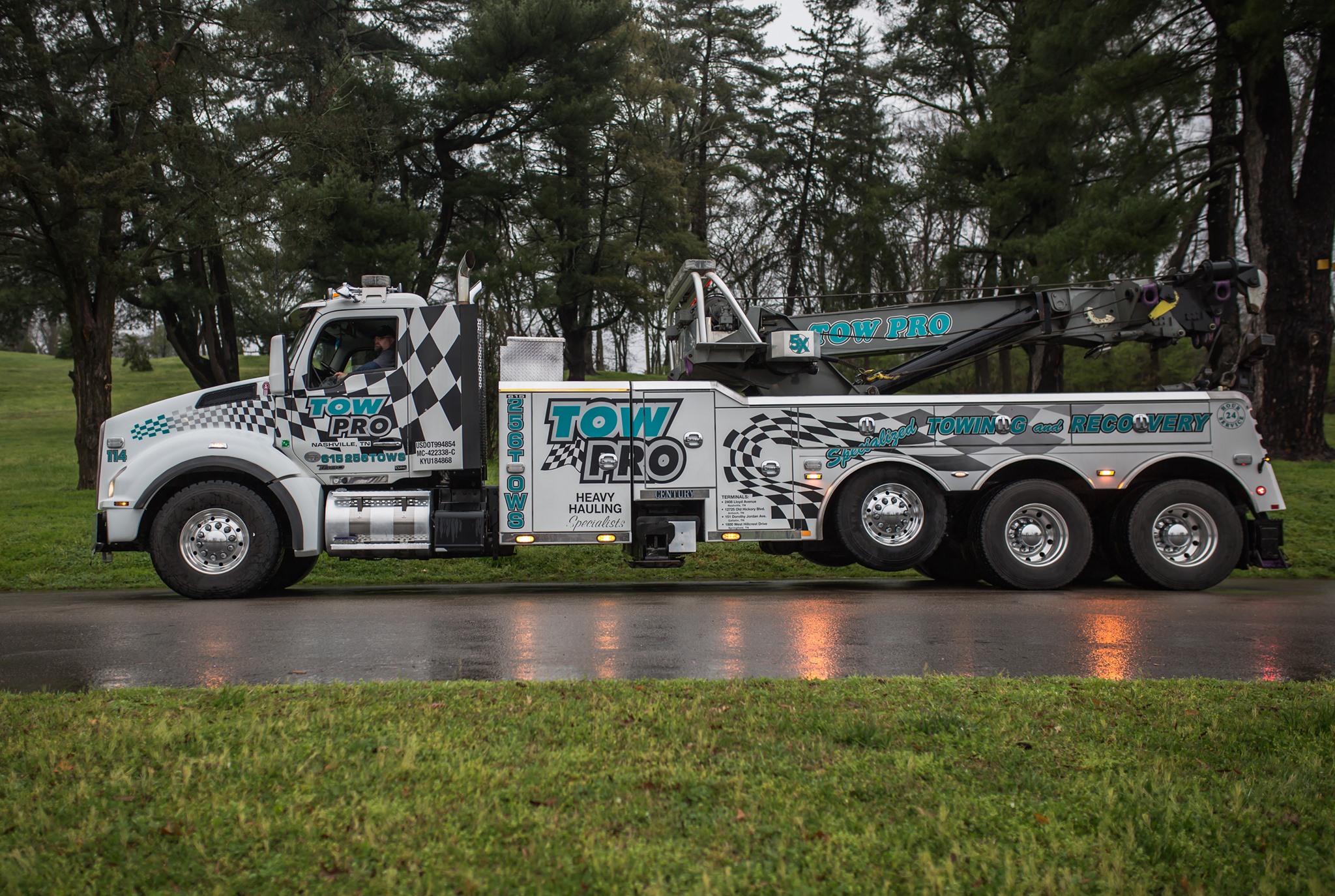 Tow Pro heavy-duty truck parked on a wet road surrounded by grass and tall trees in Nashville, showcasing the company’s professional branding and specialized towing abilities.