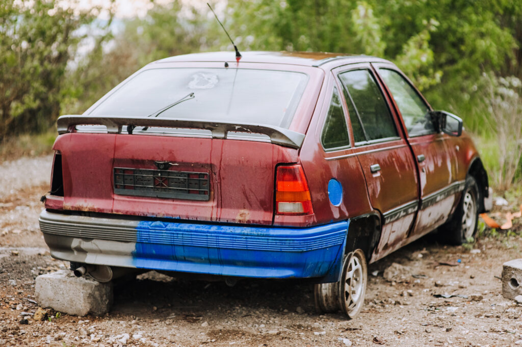 An old, rusted red junk car sitting on cinder blocks in a driveway, illustrating the need for professional junk car removal services in Nashville.