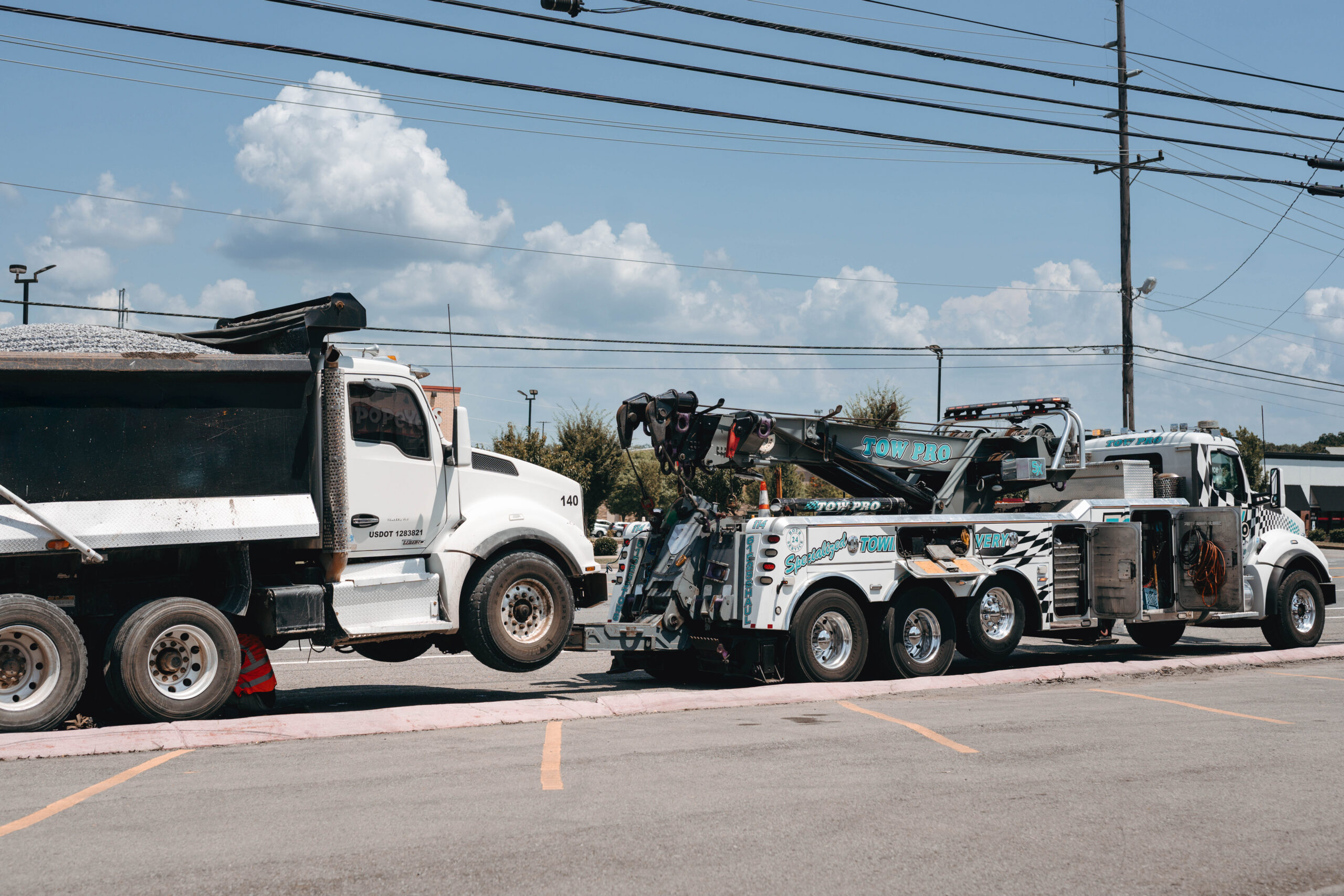 A Tow Pro heavy-duty wrecker truck successfully lifting and towing a large dump truck, demonstrating expert wrecker truck driver services in Middle Tennessee.